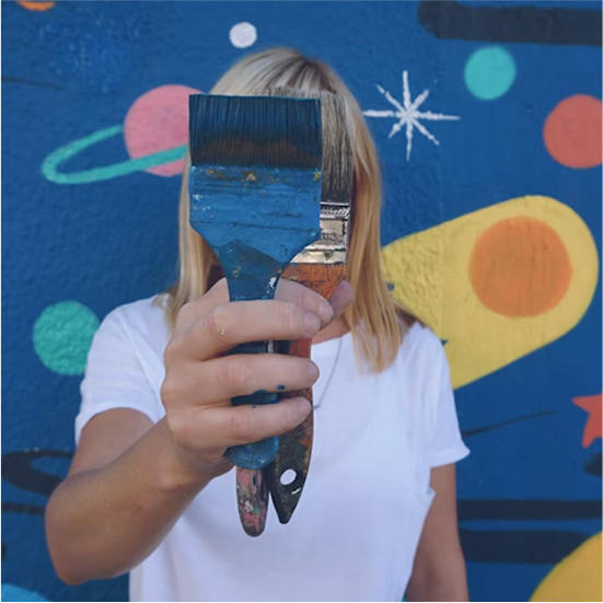 a person covering their face with a paintbrush